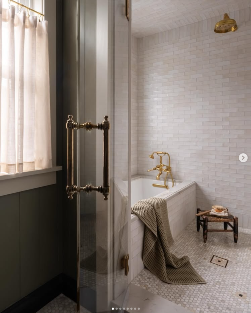 Entire bathroom tub around with small subway tile and marble surround bathtub and gold faucet.