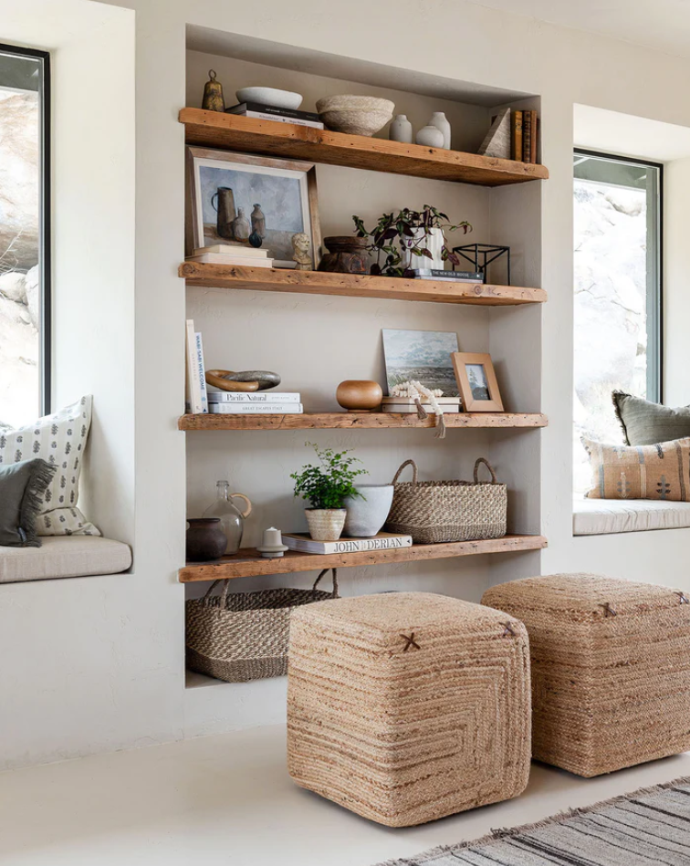 Open shelving with lots of decor items and woven ottomans in front of them.